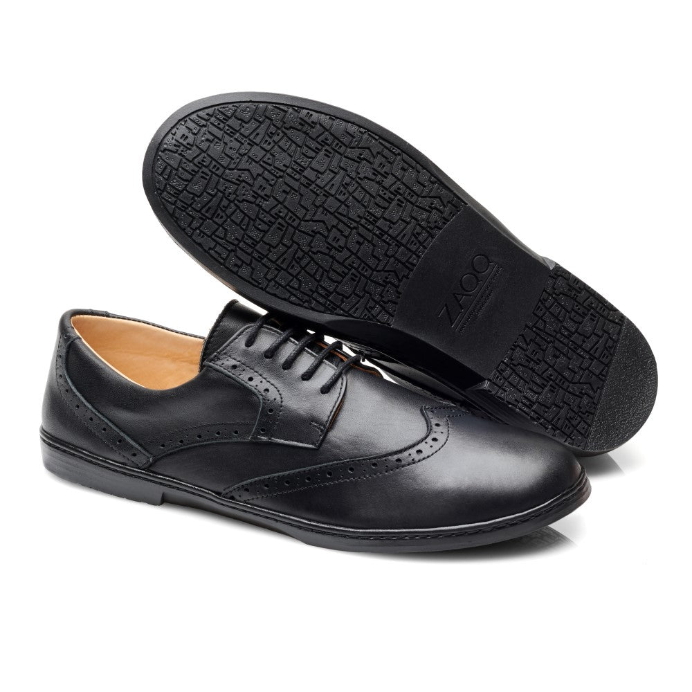 Seitenansicht eines Paars BRIQ Brogue Waterproof Black von ZAQQ, aus schwarzem Leder gefertigt und mit dekorativen Perforationen für einen zeitlosen Look.