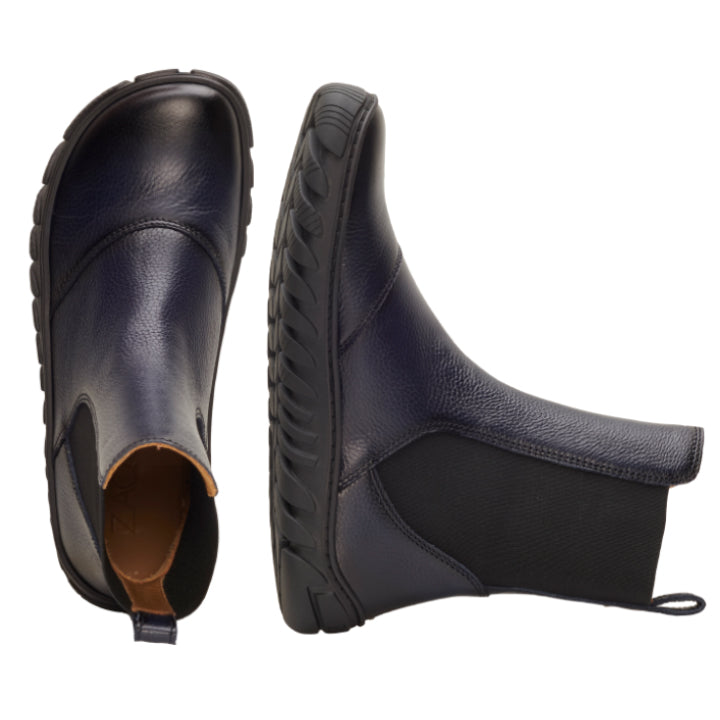 Die ELASTIQ Blue Chelsea Boots von ZAQQ werden aus verschiedenen Perspektiven in Szene gesetzt. Ein Stiefel steht aufrecht, während der andere auf der Seite liegt und die elastischen Seiteneinsätze und die ULTRAGRIP-Sohle für besseren Halt zur Schau stellt.