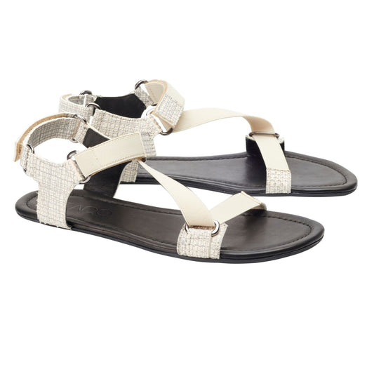 Wir präsentieren die MIQA Beige von ZAQQ: ein stilvolles Paar beige-schwarzer Sandalen mit gekreuzten Riemen und einer Schnalle auf der Rückseite, gefertigt aus hochwertigem Veloursleder. Mit einer flexiblen Sohle für ultimativen Komfort verbinden diese Barfußsandalen Stil mit Funktionalität und werden elegant vor einem weißen Hintergrund präsentiert.