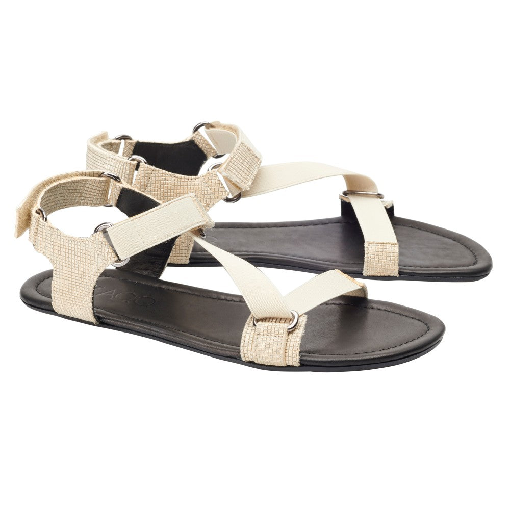 Wir präsentieren die ZAQQ MIQA Gold, ein Paar beigefarbene Barfußsandalen mit Riemensystem und schwarzer Sohle. Diese Sandalen mit verstellbaren Knöchelriemen und minimalistischem Flair bieten sowohl Komfort als auch Stil für jeden Anlass.