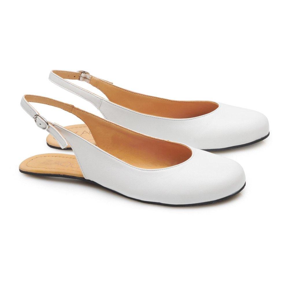 PINQ White von ZAQQ ist ein Paar weiße Slingback-Ballerinas mit abgerundeter Spitze und verstellbaren Knöchelriemen. Die Schuhe haben eine hellbraune Innensohle und eine schwarze Sohle, die sich von der Seite elegant vor einem schlichten weißen Hintergrund abhebt.