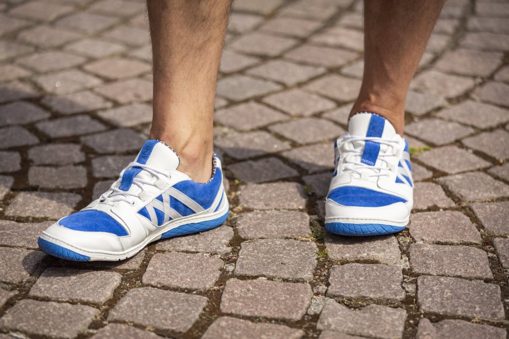 Mit dem QENDRIQ Blue von ZAQQ schlendert man über einen Kopfsteinpflasterweg. Diese eleganten Sneaker mit blauen Wildlederakzenten und weißen Schnürsenkeln verkörpern perfekt ihre stilvolle Essenz.