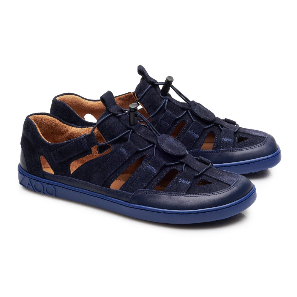 Wir präsentieren den QLEAR Blue von ZAQQ: ein Paar marineblaue, lässige Outdoorschuhe mit offenem, gewebtem Design und verstellbaren Schnürsenkeln. Diese Schuhe haben eine auffällige blaue Sohle und ein orangefarbenes Futter, was sie vor einem schlichten weißen Hintergrund zu einer stilvollen und dennoch funktionalen Ergänzung für jede Umgebung macht.