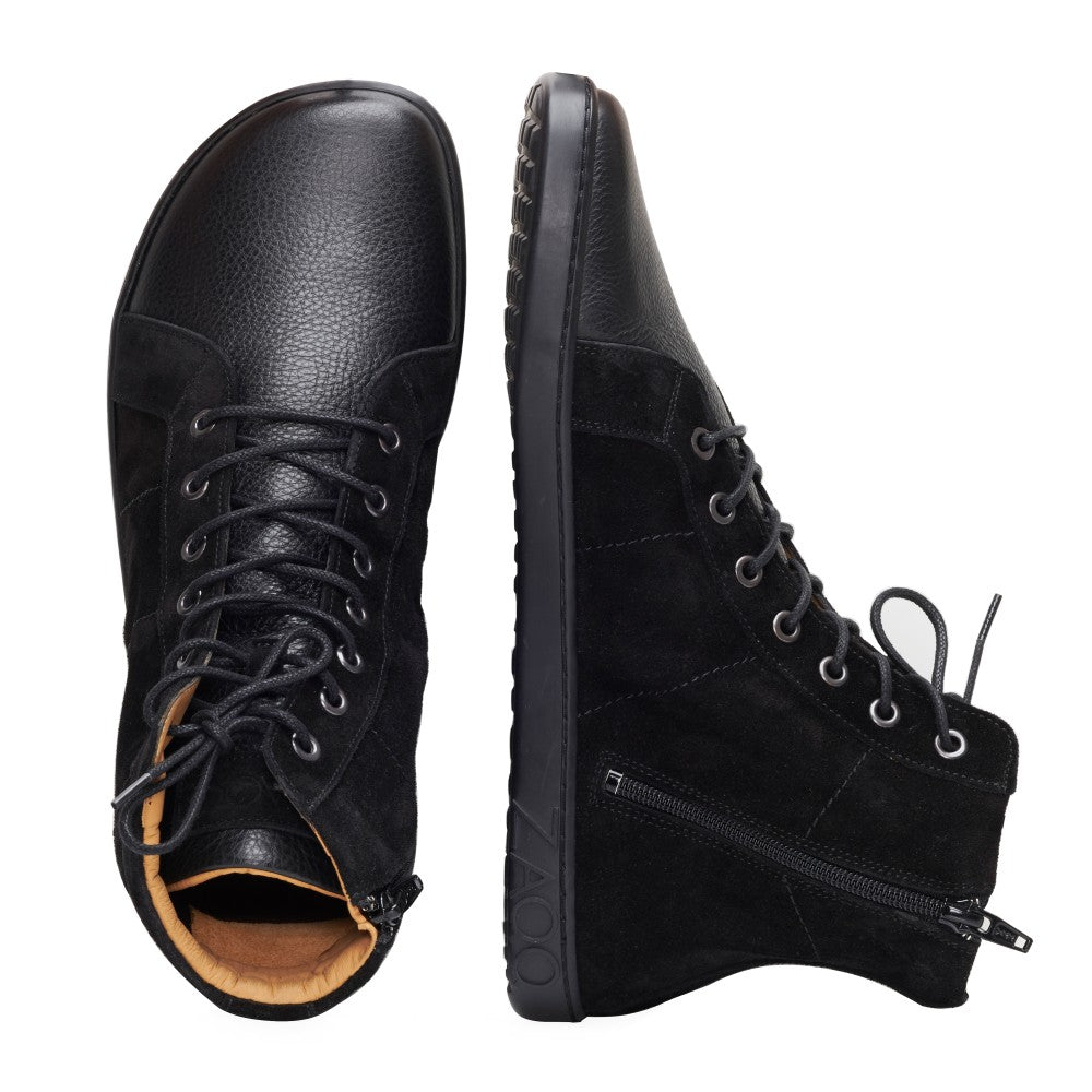 Wir präsentieren den QORE High Black von ZAQQ – diese stylischen schwarzen High-Tops bestehen aus einer Mischung aus strukturiertem Leder und Veloursleder-Wildleder. Ein Schuh steht aufrecht und hebt seine Schnürsenkel und Ösen hervor, während der andere auf der Seite liegt und einen Blick auf den Reißverschluss und die Sohle für einen klassischen Sneaker-Look bietet.