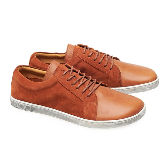 Die QORE Low Sierra Sneaker von ZAQQ sind ein stylisches Paar aus glattem braunem Leder mit Wildledereinsätzen und weißen Sohlen mit geprägten Details. Diese Schuhe haben braune Schnürsenkel und zeigen ein lässiges und modernes Design.