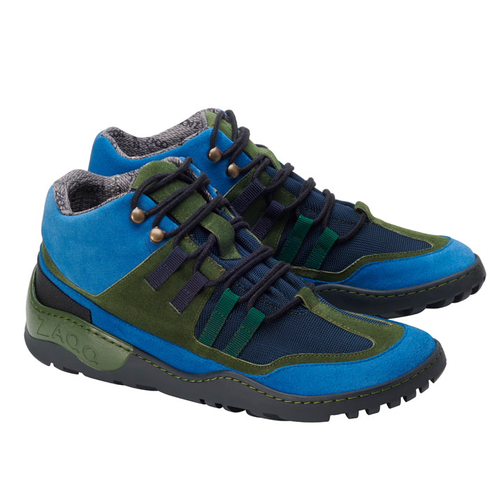 Die ESQAPE Blue Green Waterproof Sneaker von ZAQQ bestechen durch ihr leuchtend blaues und grünes Wildleder, ergänzt durch schwarzes Mesh und dunkle Schnürsenkel. Sie verfügen über das markante ZAQQ TERRA Sohlendesign für die Sohlen, während das graue wollähnliche Innenfutter für Komfort sorgt. Der Markenname ZAQQ ist prominent auf der Außensohle eingeprägt.