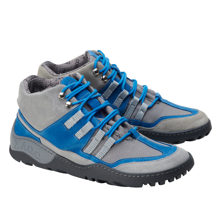 Wir präsentieren die SQOUT Grey Blue Waterproof-Schuhe von ZAQQ, die ein modernes Design mit blauen Schnürsenkeln, grauem Mesh-Gewebe und auffälligen blauen Akzenten auf einer robusten schwarzen Sohle präsentieren. Ihr sportliches Aussehen wird durch eine atmungsaktive Qualität ergänzt, was sie ideal für Outdoor-Abenteuer macht.