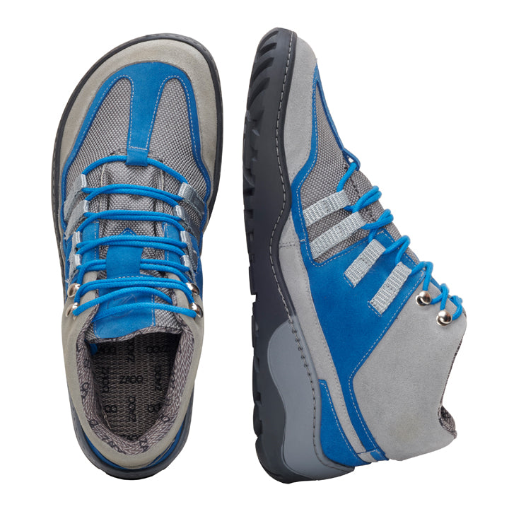 Die wasserdichten Wanderschuhe SQOUT Grey Blue von ZAQQ werden in Draufsicht und Seitenansicht präsentiert, wobei die blauen Akzente und grauen Nähte hervorgehoben werden. Das Design zeichnet sich durch eine strukturierte Sohle und blaue Schnürsenkel aus, die ihr stilvolles Erscheinungsbild betonen. Als Barfußschuh bieten sie ein atmungsaktives Tragegefühl für ultimativen Komfort auf all Ihren Wanderungen.