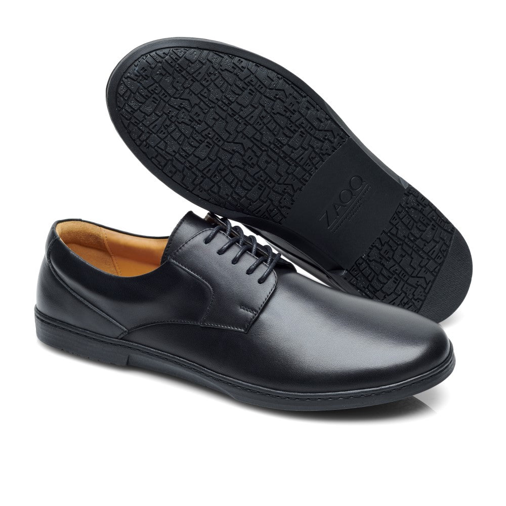 Der BRIQ Black von ZAQQ ist ein Paar schwarzer Lederschuhe mit Schnürverschluss und zeitlosem Design. Ein Schuh steht aufrecht und zeigt das Obermaterial aus glattem Leder, während der andere geneigt ist und die elegant gemusterte Sohle zeigt. Die Innenseite bietet einen hellbraunen Kontrast und verkörpert einen eleganten Businessschuh-Stil.