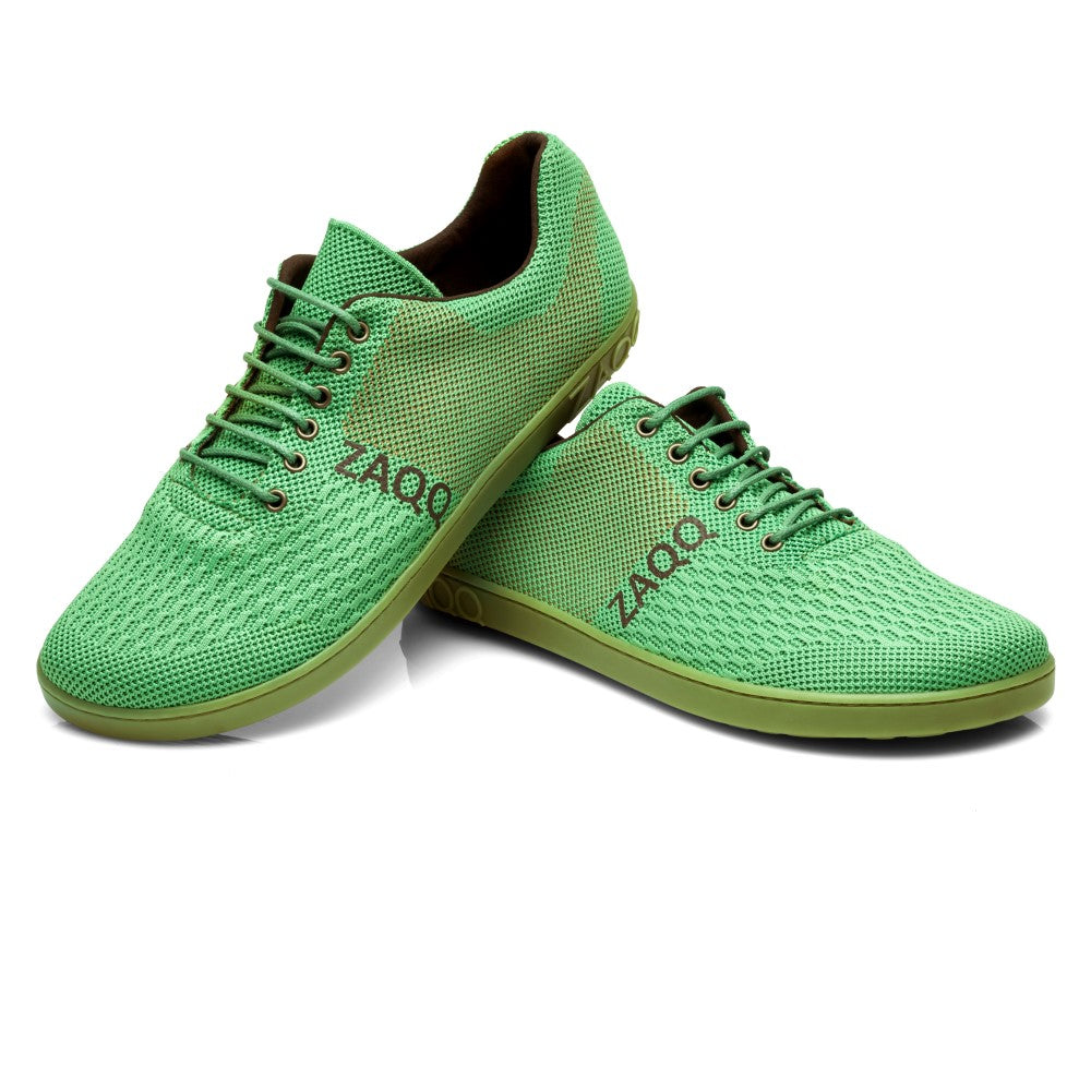 Der QNIT Lime, ein leuchtend grünes Paar Sportschuhe mit Mesh-Design und weißer Sohle, bietet außergewöhnlichen Komfort. Ein Schuh steht aufrecht, während der andere auf der Seite liegt und den Markennamen ZAQQ zeigt und das veganfreundliche Barfußschuh-Konzept unterstreicht.