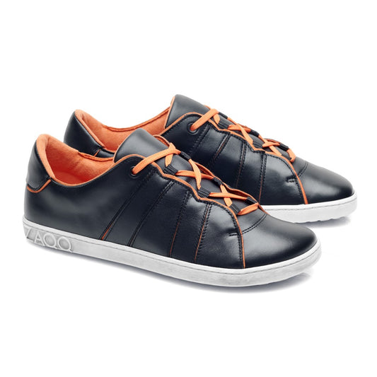 Ein Paar schicke QQQ Low Black Orange Sneaker von ZAQQ, mit leuchtend orangefarbenen Schnürsenkeln und Innenfutter. Die Schuhe bestechen durch veganes Futter und eine weiße Sohle mit kreisförmigem Muster in Fersennähe. Schräg positioniert, zeigen sie ihr stylisches Design.